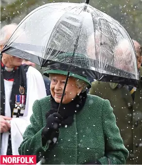  ??  ?? Taking shelter: The Queen braves the snow as she leaves church NORFOLK