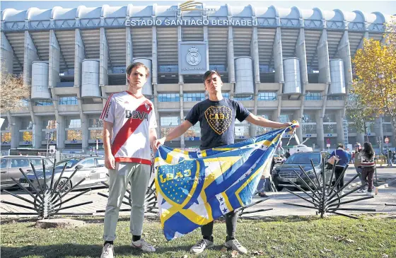  ??  ?? River Plate fan German Lopez, left, poses with his brother and Boca Juniors supporter Gonzalo Lopez in front of Real Madrid’s Santiago Bernabeu stadium.