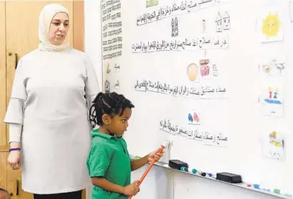  ?? KIM HAIRSTON/BALTIMORE SUN PHOTOS ?? Rihab Riskak, a kindergart­en teacher, watches as Gabrielle Davis, 5, works in Arabic at the Baltimore Internatio­nal Academy, a charter school. The academy wants to open another location; it is one of six applicatio­ns the Baltimore school board is considerin­g.