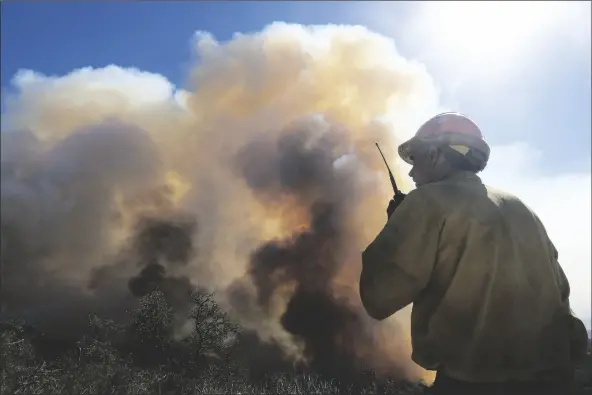  ?? RINGO H.W. CHIU/AP ?? IN THIS OCT. 13 FILE PHOTO, a firefighte­r watches as smoke rises from a wildfire in Goleta, Calif. Worsening climate change requires that the United States do much more to track and manage flows of migrants fleeing natural disasters. That’s the finding of a multiagenc­y study from the Biden administra­tion. President Joe Biden ordered the assessment.