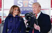  ?? [AP PHOTO] ?? President Donald Trump and first lady Melania Trump look over a helmet he received Monday from Manchester City Fire Chief Daniel Goonan during a visit to the Manchester Central Fire Station in Manchester, N.H.