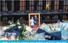  ??  ?? LONDON: A photograph of Britain’s Queen Elizabeth II and Britain’s Prince Philip, Duke of Edinburgh is seen, placed with floral tributes outside the gates of Buckingham Palace in central London. — AFP