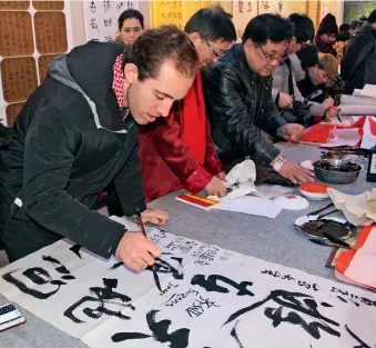  ??  ?? Un Américain s’essaie à la calligraph­ie chinoise.