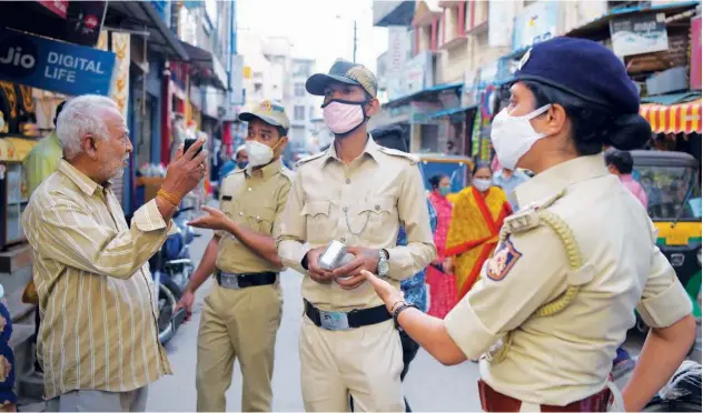  ?? Agence France-presse ?? ↑ Police impose fines on a man (left) for not wearing a face mask in Bengaluru, Karnataka, on Tuesday.