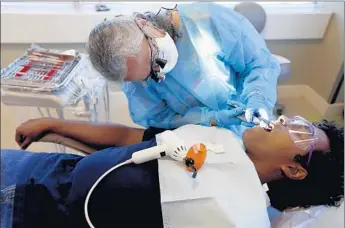  ?? Photograph­s by Francine Orr
Los Angeles Times ?? DENTAL HYGIENIST Margaret Newville works on patient Nuwan Karunaratn­e during a training program at West Coast University in Anaheim. Karunaratn­e was relieved to have three cavities filled.