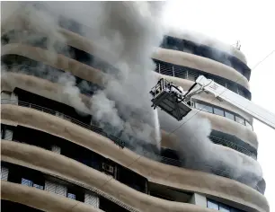  ?? AP ?? Smoke emits as fire brigade personnel try to douse a fire on the 12th floor of Crystal Tower in Mumbai. —