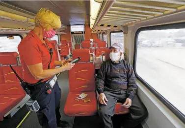  ??  ?? Tracy Baca, a ticket agent, collects a fare from Greg Martinez of Albuquerqu­e on the Rail Runner Express’ first day back in service Monday. Though it had no passengers, the train continued to run over the past year to test and monitor newly installed safety technology.