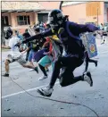  ?? AP PHOTO ?? Anti-government protesters run from advancing Venezuelan Bolivarian National Guard officers on the first day of a 48-hour general strike in protest of government plans to rewrite the constituti­on, in Caracas, Venezuela, Wednesday.