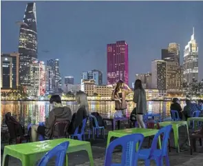  ?? — Bloomberg ?? Fast growth: Customers at a cafe along the saigon river in Ho Chi Minh City. speeding up public spending will be a significan­t factor for the city to reach its growth target for 2024.