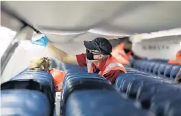  ?? RICARDO RAMIREZ BUXEDA/ORLANDO SENTINEL ?? Delta Air Lines employees clean the cabin of a Boeing 757 at Gate 71 of the Orlando Internatio­nal Airport. Airline woprkers are worried about their jobs as the CARES Act deadline nears.