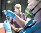  ??  ?? Teresa Hohner prepares a vaccine Tuesday as Barbara Cyzyk waits at the Porter County Expo Center.