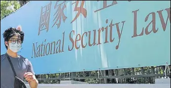  ?? AFP ?? A man walks past a government banner about the national security law in Hong Kong.