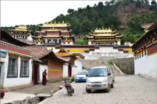  ??  ?? A monk pauses to look at a taxi arriving for pickup at Sertri Monastery, one of two in Langmusi, a small town that straddles China’s Sichuan and Gansu provinces.