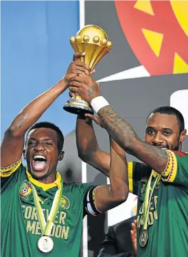  ?? /AFP ?? Treasure: Cameroon’s Benjamin Moukandjo, left, and Nicolas Nkoulou, who scored his side’s first goal in the final, hoist the trophy.