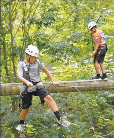  ?? KIM HAIRSTON/BALTIMORE SUN ?? Twelve-year-olds Max Mergerian, left, and Jacob Rassi, both of Bel Air, make their way through the high ropes challenge course at Terrapin Adventures. They are at the aerial adventure park with classmates from Harford Day School.