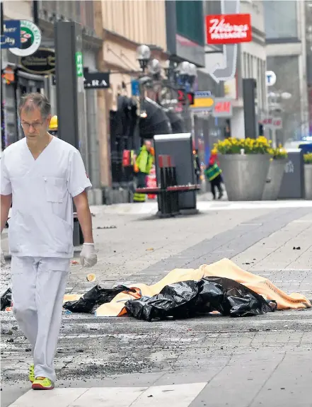  ??  ?? Two bodies are covered with blankets with medics on the scene after a stolen lorry crashed into a department store in Stockholm, killing three people. Far left: one of the victims is carried away after the incident on the capital’s Drottningg­atan