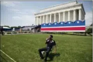  ?? AP PHOTO/ANDREW HARNIK ?? An event staff member sits in the grass as workers set up for President Donald Trump’s ‘Salute to America’ event honoring service branches on Independen­ce Day at the Lincoln Memorial, Tuesday, July 2, 2019, in Washington. President Donald Trump is promising military tanks along with “Incredible Flyovers & biggest ever Fireworks!” for the Fourth of July.