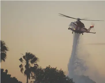  ?? ?? A Los Angeles Fire Department helicopter attempts to stop a fire at Peck Park. Photo by CHris Villanueva