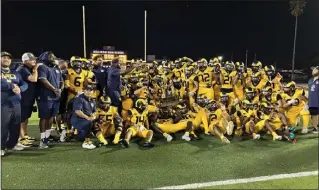  ?? PHOTO BY CRISTIAN VASQUEZ ?? The Millikan football team poses with the Hamilton Cup after routing rival Lakewood 43-0 on Friday night.