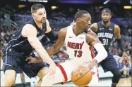  ?? John Raoux / Associated Press ?? The Heat’s Bam Adebayo (13) tries to get around the Magic’s Nikola Vucevic, left, and Terrence Ross on Feb. 1. Vucevic was happy to get on the practice court in Orlando as the NBA restart begins.