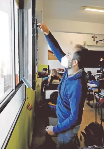  ??  ?? Un docente abre una ventana en una clase de un centro de Córdoba. A la derecha,