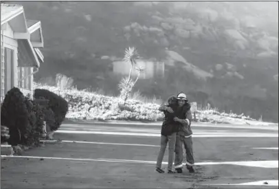  ?? The Associated Press ?? INTACT: Firefighte­r Simon Garcia, of Heartland Fire Dept., gets a hug from a woman who did not give her name after she arrived to find her house was intact Friday in the Rancho Monserate Country Club in Fallbrook, Calif. The wind-swept blazes have...