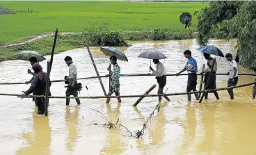  ?? /AFP Photo ?? Soaking wet: Rohingya Muslim refugees cross floodwater in Thyangkhal­i refugee camp near the Bangladesh town of Ukhia on Sunday. Myanmar’s de facto leader, Aung San Suu Kyi, is to give a nationally televised speech on the issue on Tuesday.