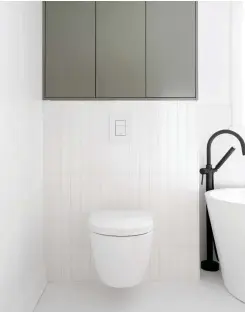  ?? ?? Qui dit petite salle de bain dit mobilier suspendu pour libérer de l'espace au sol. Au-dessus de la toilette murale, un rangement pour les serviettes exploite toute la hauteur du mur de façon graphique, en rappel de la céramique longitudin­ale murale.