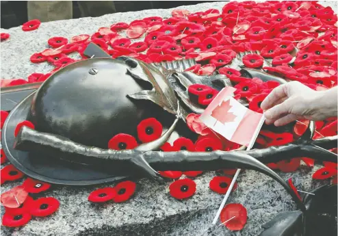  ?? The cana dian press files ?? After ceremonies on Nov. 11 at the National War Memorial in Ottawa, Canadians often removed
their poppies to leave them on the Tomb of the Unknown Soldier.