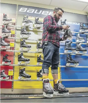  ?? SHAUGHN BUTTS ?? Reporter Juris Graney tries on a pair of skates at United Cycle as part of his education in learning how to play the game of hockey.