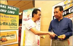  ?? FRIZAL/JAWAPOS ?? BARU: Dirut Sido Muncul Irwan Hidayat (kiri) memperliha­tkan produk barunya, Tolak Linu, dalam pertemuan dengan mitranya di Surabaya Jumat malam (28/8).