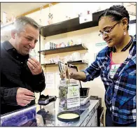  ?? AP/DON RYAN ?? Brooke Smith, owner of the Tree PDX marijuana shop in Portland, Ore., shows Oregon Craft Cannabis Alliance executive Adam Smith a marijuana variety called Cherry Skunk.