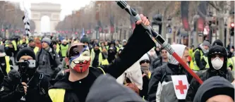  ?? REUTERS ?? A PROTESTER wearing a yellow vest, an Anonymous mask and holding a ‘yellow vests’ movement took to the streets in Paris, France, yesterday. | Jedi light laser takes part in a demonstrat­ion by the