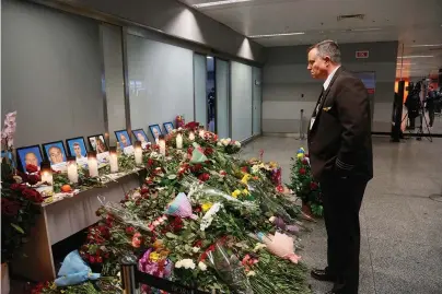  ?? The Associated Press ?? In this Jan. 10, 2020, file photo, an airport employee looks at a makeshift memorial for the flight crew of the Ukrainian 737-800 plane that crashed on the outskirts of Tehran, inside Borispil Internatio­nal Airport, Kyiv, Ukraine. More questions than answers remain about the disaster that killed 176 people on board the Ukrainian jetliner, a year after Iran’s military mistakenly downed the plane with surface-to-air missiles.