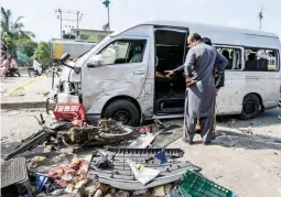  ?? ?? NARROW ESCAPE — Pakistani investigat­ors examine a damaged van at the site of a suicide attack in Karachi, Pakistan, Friday, April 19, 2024. Five Japanese nationals traveling in a van narrowly escaped a suicide attack when a suicide bomber detonated his explosive-laden vest near their vehicle in Pakistan's port city of Karachi on Friday, wounding three passers-by, police said. (AP)