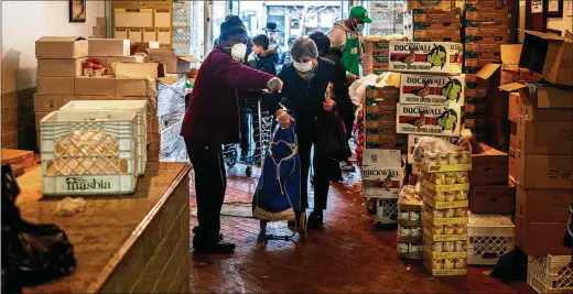  ?? DEMETRIUS FREEMAN / NEW YORK TIMES ?? A volunteer helps a client find the food she needs at the Masbia Soup Kitchen in New York City last month. Demand for food assistance is rising at an unpreceden­ted rate, just as the nation’s food banks are being struck by shortages of donated food and volunteer workers.