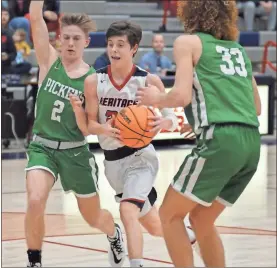  ?? Michelle Petteys, Heritage Snapshots ?? Heritage’s Cade Collins slices in between two Pickens defenders on his way to the hoop. Collins had 18 points in the Generals’ setback to the Dragons last Tuesday night.