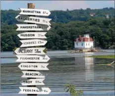 ?? TANIA BARRICKLO — DAILY FREEMAN FILE ?? A sign post showing the distances to various communitie­s along the Hudson River stands along western shore of the river at the Esopus Meadows Preserve in the town of Esopus. In the background is the Esopus Meadows Lighthouse.
