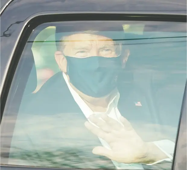  ?? ALEX EDELMAN / AFP via Gett y Images ?? U. S. President Donald Trump waves from the back of a car in a motorcade outside Walter Reed Medical Center in Bethesda, Md., on Sunday. The president, infectious with COVID-19, acknowledg­ed supporters who have kept vigil outside the hospital and then quickly returned to the facility.