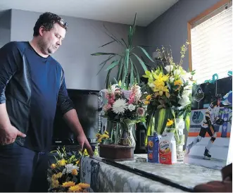  ?? MICHELLE BERG ?? Scott Thomas stands in his Saskatoon home next to a table filled with flowers, food and other items that honour his son Evan Thomas, one of the Humboldt Broncos killed in last Friday’s bus crash. A funeral for the 18-year-old will be held Monday at...