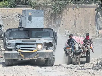  ?? AFP ?? An Iraqi military vehicle passes displaced Iraqi boys returning to their homes in West Mosul’s Oreibi neighbourh­ood after government forces retook control of the area from the Islamic State group during the ongoing offensive against the jihadists on...