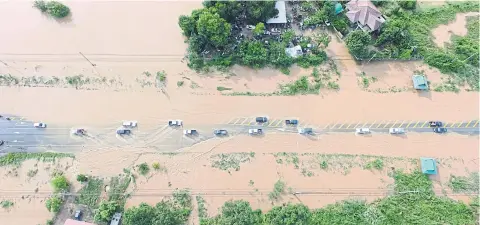  ??  ?? Muddy water run-off from the Phetchabun mountain range floods one of the main roads near the Wang Thong Hospital in Wang Thong district of Phitsanulo­k. The flood situation in many provinces has eased after tropical depression Doksuri battered wide...