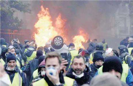  ??  ?? Manifestan­tes con chalecos amarillos se enfrentaro­n ayer a la policía e incendiaro­n vehículos cerca del Arco del Triunfo de París, Francia.