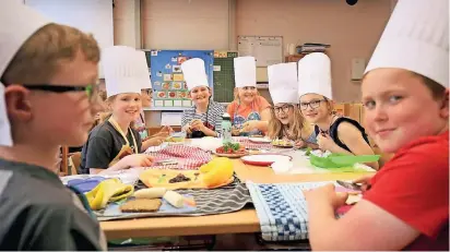  ?? RP-FOTO: ACHIM BLAZY ?? Die Drittkläss­ler der Suitberuss­chule lernen, wie man gutes Essen lecker und frisch zu bereitet. Im Hintergrun­d ist die Ernährungs­pyramide zu sehen.