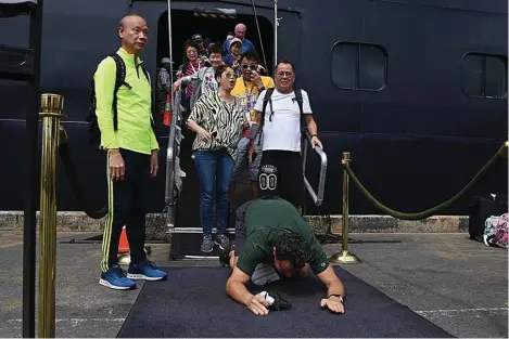  ?? TANG CHHIN SOTHY/AFP ?? SUJUD SYUKUR:
Seorang penumpang kapal Westerdam mencium tanah begitu diperboleh­kan turun di Pelabuhan Sihanoukvi­lle, Kamboja, kemarin. Mereka sudah dua pekan berada di kapal tanpa ada kepastian mendarat. Foto kanan, seorang anak menunjukka­n kertas ucapan terima kasih kepada Kamboja yang memperbole­hkan mereka mendarat.