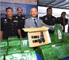  ??  ?? Mohmad Salleh (third right) shows the pistol and drugs hidden in green tea packets during the press conference. — Bernama photo