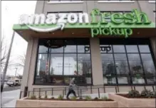  ?? ELAINE THOMPSON — THE ASSOCIATED PRESS FILE ?? An Amazon worker wheels back a cart after loading a bag of groceries into a customer’s car at an AmazonFres­h Pickup location in Seattle.