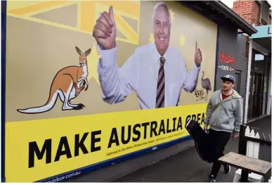  ?? — AFP ?? Australia’s own Trump:
A man walking past a billboard of Palmer in Melbourne.