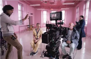  ?? JESSICA KOURKOUNIS/UNIVERSAL PICTURES ?? Writer-director M. Night Shyamalan (left) talks to James McAvoy, Bruce Willis and a crew member in the hospital's pink day hall, which is the site of a major scene.