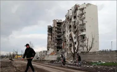  ?? REUTERS ?? Men sort and remove garbage near a residentia­l building heavily damaged during Ukraine-russia conflict in the southern port city of Mariupol, Ukraine, on Friday.